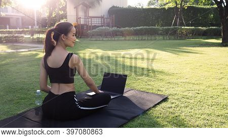 A Sporty Woman Or Online Instructor In Sportswear Is Sitting And Practicing Yoga On The Mat With Com