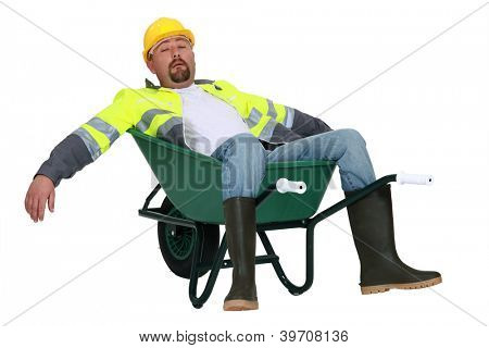 Exhausted builder laying in wheelbarrow