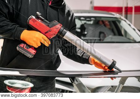 Glazier Applying Rubber Sealing To Windshield In Garage, Close Up. High Quality Photo