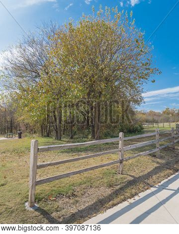 Scenic Park Entrance With Rustic Wooden Fence And Pathway With Colorful Fall Foliage In Plano, Texas