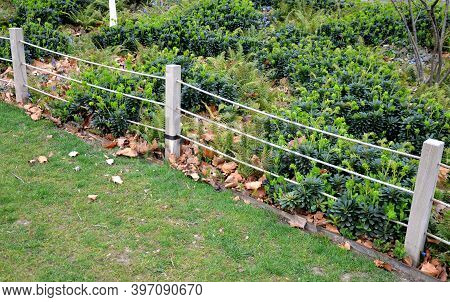 A Rope Fence In The City Park Protects Flower Beds From The Entrance Of People Dogs Or Bicycle Entry