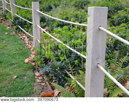 A Rope Fence In The City Park Protects Flower Beds From The Entrance Of People Dogs Or Bicycle Entry