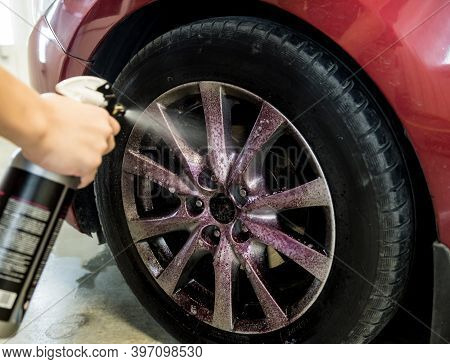 Service Worker Washing Car Wheell At A Car Wash.