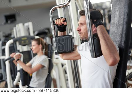 Athletic Gym Trainer Doing Chest Press Exercise. Young Handsome Man Using Exercise Equipment At Gym.