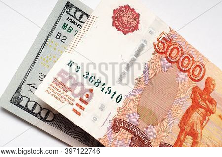 Russian Banknote Of 5000 Rubles And A Note Of 100 Dollars On A White Paper Background Close-up. Deva