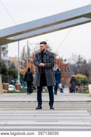 Handsome Young Man In Grey Coat And Suit Crossing The Street. Full Length Photo. Closeup.