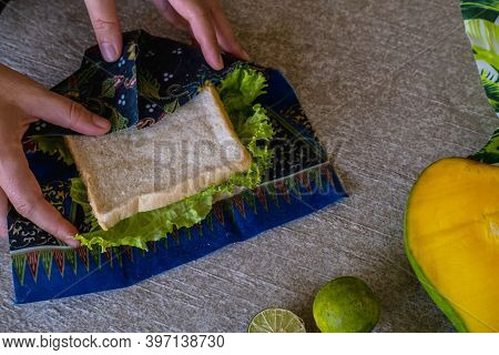 Close Up Of Woman Wrapping Sandwich And Fruits In Environmentally Safe Beeswax Wrap. Reusable Eco-fr