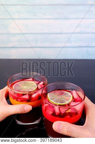 Vertical Image Of Man And Woman's Hand Holding Glass Of Red Wine Sangria On Black Table