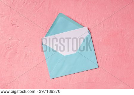 A Greeting Card Or Invitation Mockup In A Blue Envelope, Shot From The Top On A Pink Background With