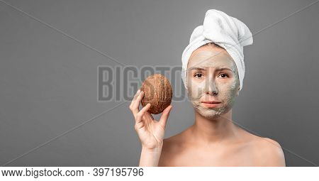 Beautiful Young Woman With Facial Coconut Mask On The Face Smashes Coconut For Spa Treatment. Organi
