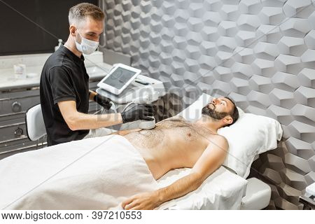 Man During An Ultrasound Liposuction Procedure At Luxury Spa Salon. Doctor Working On Abdomen Area