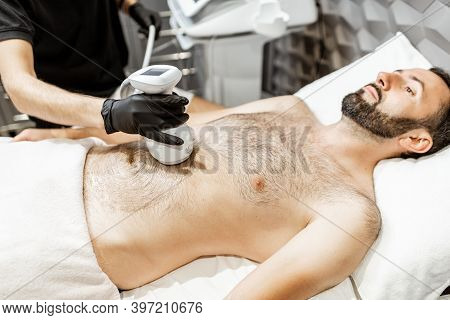 Man During An Ultrasound Liposuction Procedure At Luxury Spa Salon. Doctor Working On Abdomen Area