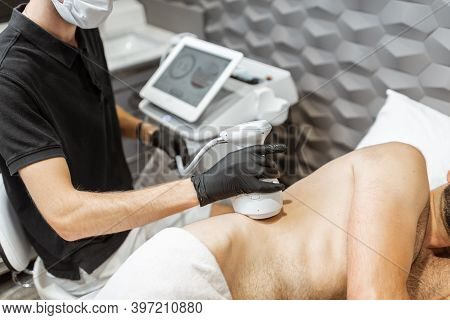 Man During An Ultrasound Liposuction Procedure At Luxury Spa Salon. Doctor Working On Waist Side Are