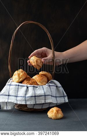 Basket With Traditional French Gougeres - Savory Cheese Pastry And Female Hand Taking One Of The Bun