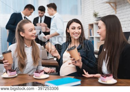 Two Young Girls Are Laughing At Work Annoying Boss. Two Women Are Standing In The Office With Papers