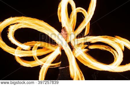 Sensual Woman Artist Perform Fiery Twirly Trails By Spinning Flaming Pois During Fire Performance In