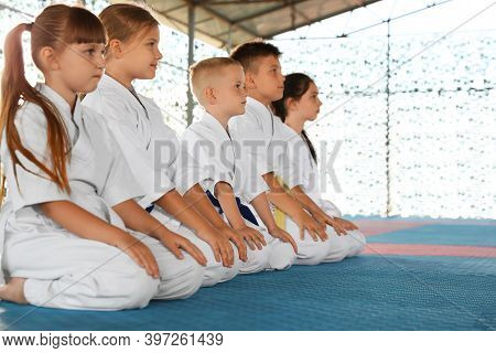 Children In Kimono Sitting On Tatami Outdoors. Karate Practice
