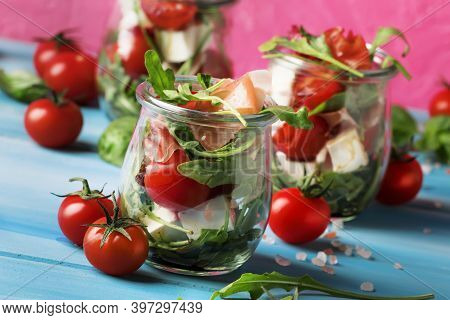 Summer Salad With Arugula, Soft Cheese, Cherry Tomatoes And Prosciutto In Glass Jars, Trendy Pink Bl
