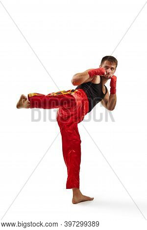 Athletic Fighter In Red Sports Bandages On His Hands Making Kick During Boxing Exercise, Isolated On