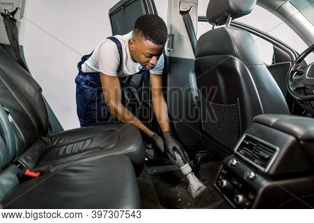 Handsome Young African American Man Auto Service Worker, Doing Professional Vacuum Cleaning Of Salon