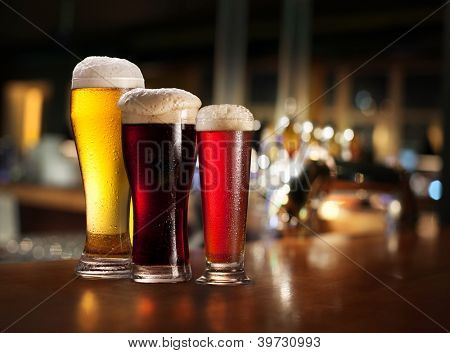 Bicchieri di birra chiara e scura su sfondo pub.