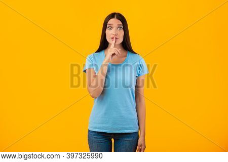 Shh, Keep Silence. Portrait Of Funny Lady Gesturing Hush Sign Posing Isolated Over Studio Yellow Bac