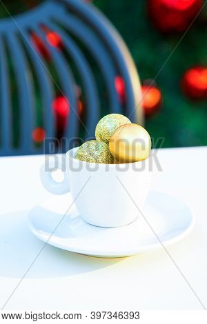 Vertical Picture Of Porcelain Coffee Cup With Golden Christmas Balls Inside. Coffee Pair On White Ta