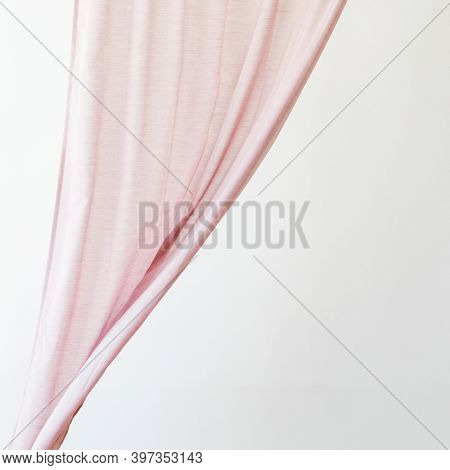 Pink drapery curtain hanging from a curtain rod