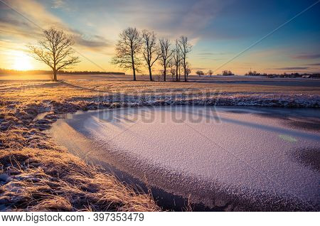 A Beautiful Frozen Pond In The Rural Scene During The Morning Golden Hour. A Winter Scenery Of North