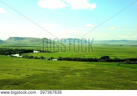 A Calm River Curving Through A Picturesque Valley On A Warm Sunny Day At The Foot Of The Mountain Ra