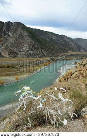 A Withered Bush With Ritual Ribbons On A Rocky Hilltop Overlooking The Bend Of A Turquoise River Flo