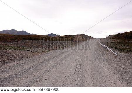 A Smooth Dirt Road With A Fence Goes Up The Hill.