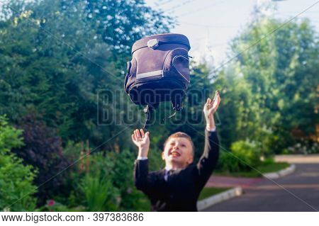 A Teenage Boy Is A European Schoolboy In A Black Suit, White Shirt. The Student Takes Off His Backpa