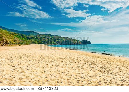 Tropical Beach With White Sand And Green Mountain Near Blue Sea In Koh Lanta Island, Thailand