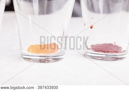Close-up Of Colored Powders Of Yellow And Red Color Poured On The Bottom Of Transparent Glasses On A