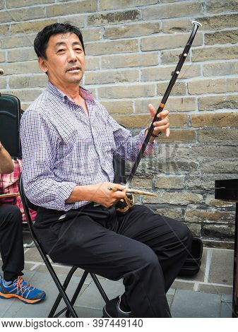 Beijing, China - September 2017: Chinese Man Playing The Chinese Violin Called Erhu In A Small Ensem