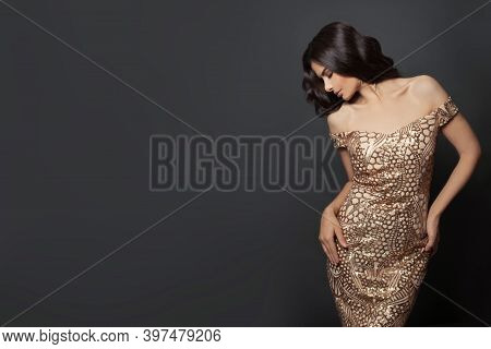 Beautiful Woman Fashion Model With Makeup And Curly Hairstyle In Gold Evening Gown On Black Backgrou