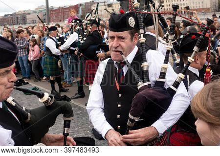 A Scottish Piper Plays A Traditional Bagpipe In The Street.