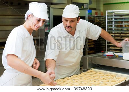 Kobieta i mężczyzna piekarz pieczenia świeżego chleba w bakehouse, wytwarzają brezn