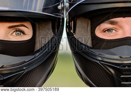 A Very Close-up Of A Man And A Woman In Motorcycle Helmets Leaning Against Each Other, Looking At Th