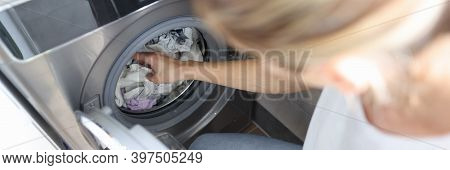 Woman Folds Clothes Into The Washing Machine. Home Help Service And Service Concept