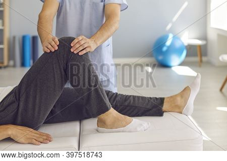Hands Of Doctor Masseur Fixing Patients Knee In Stable Position During Visit