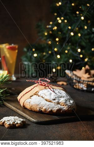 Traditional Christmas Stollen On Festive Table With Garland And Evergreen Branches.