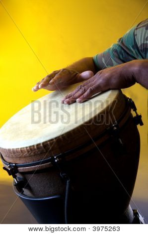 Hnědá Djembe s rukama na žlutém podkladu