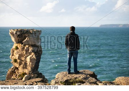 Caucasian Man In Sea Cliffs Landscape In Cabo Carvoeiro Cape Looking At Berlengas Island, In Peniche