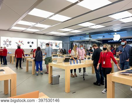 Salespeople And Customers At An Apple Store Looking At The Latest Apple Products For Sale.