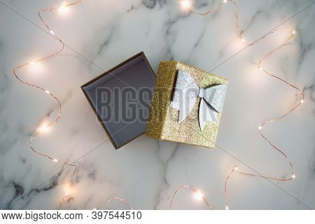 Presents And Special Occasions, Open Gift Box With Gold And Silver Glitters Surrounded By Fairy Ligh