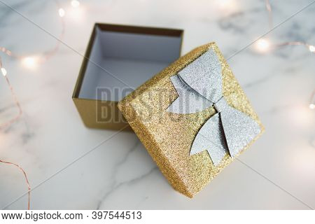 Presents And Special Occasions, Open Gift Box With Gold And Silver Glitters Surrounded By Fairy Ligh