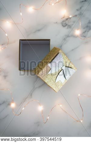 Presents And Special Occasions, Open Gift Box With Gold And Silver Glitters Surrounded By Fairy Ligh
