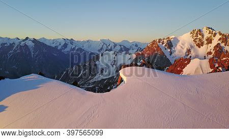 Epic Red Dawn On Top Of Snowy Mountains. Top View From A Drone. Huge Rocks Covered With Snow, The Le